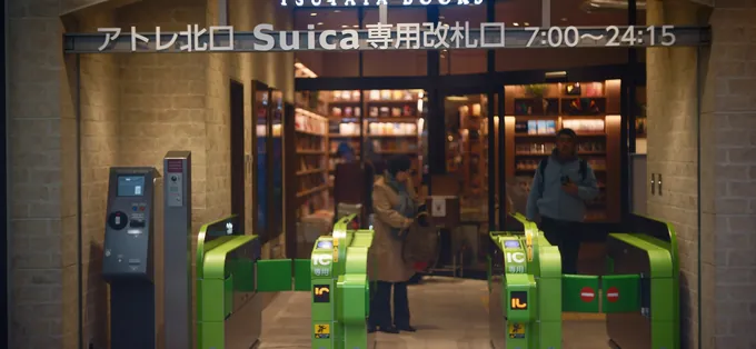 IC card ticket gates marked for Suica at a JR station exit that opens onto a bookshop
