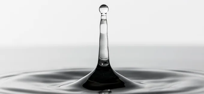 A drop of water splashing up from a still water surface