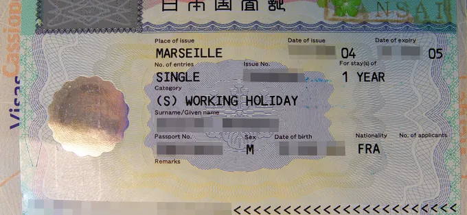 A Japanese working holiday visa in a French passport, with the holder's details blurred