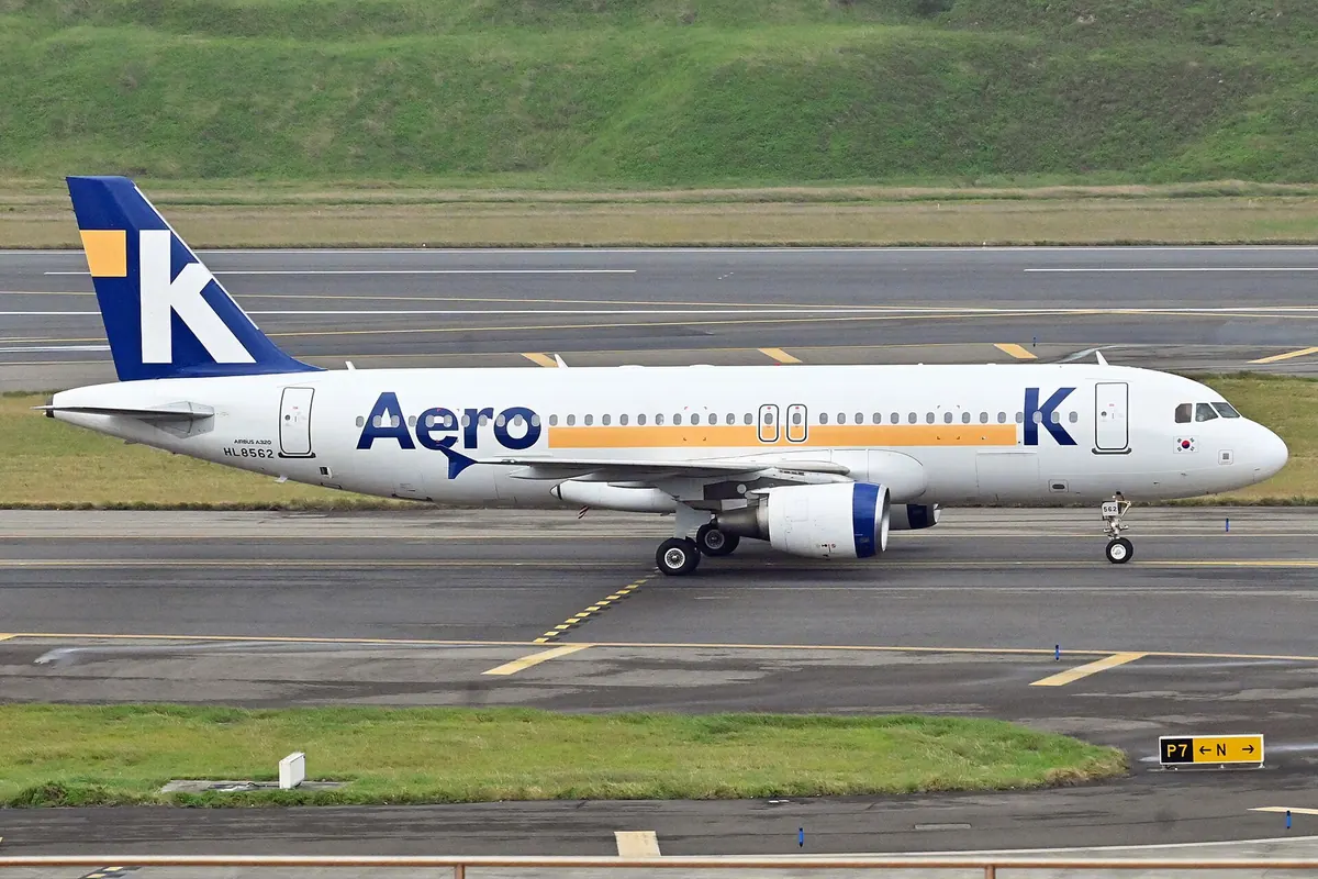 停在機場滑行道上的藍橙塗裝 Aero K A320 客機