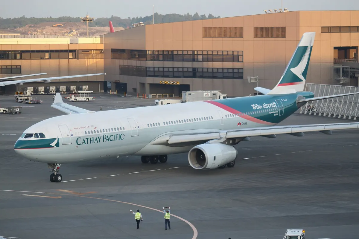 在成田国际机场停机坪滑行的 Cathay Pacific A330 客机，地勤人员指挥中