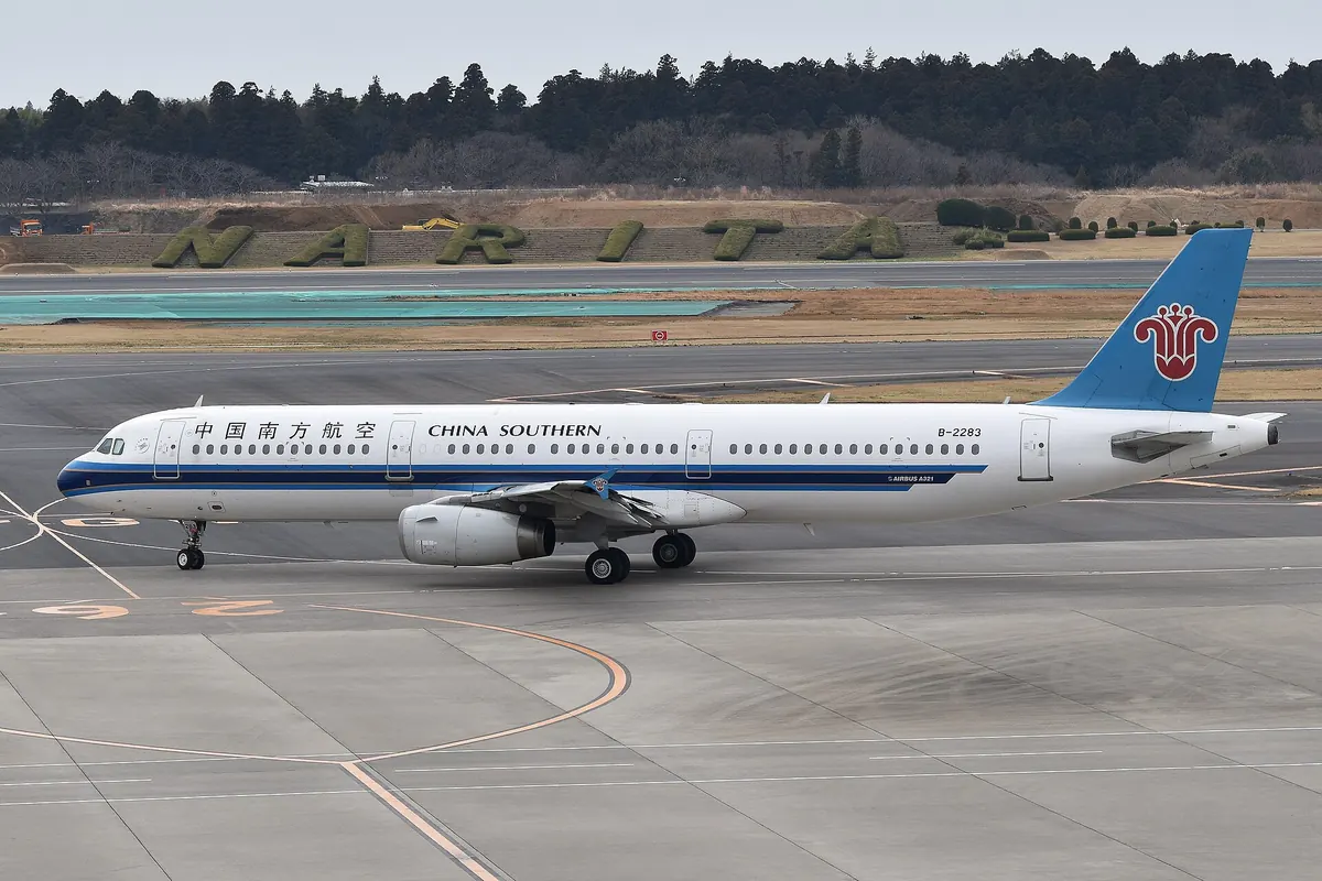 成田の標識を背に空港を走行する中国南方航空のA321型機