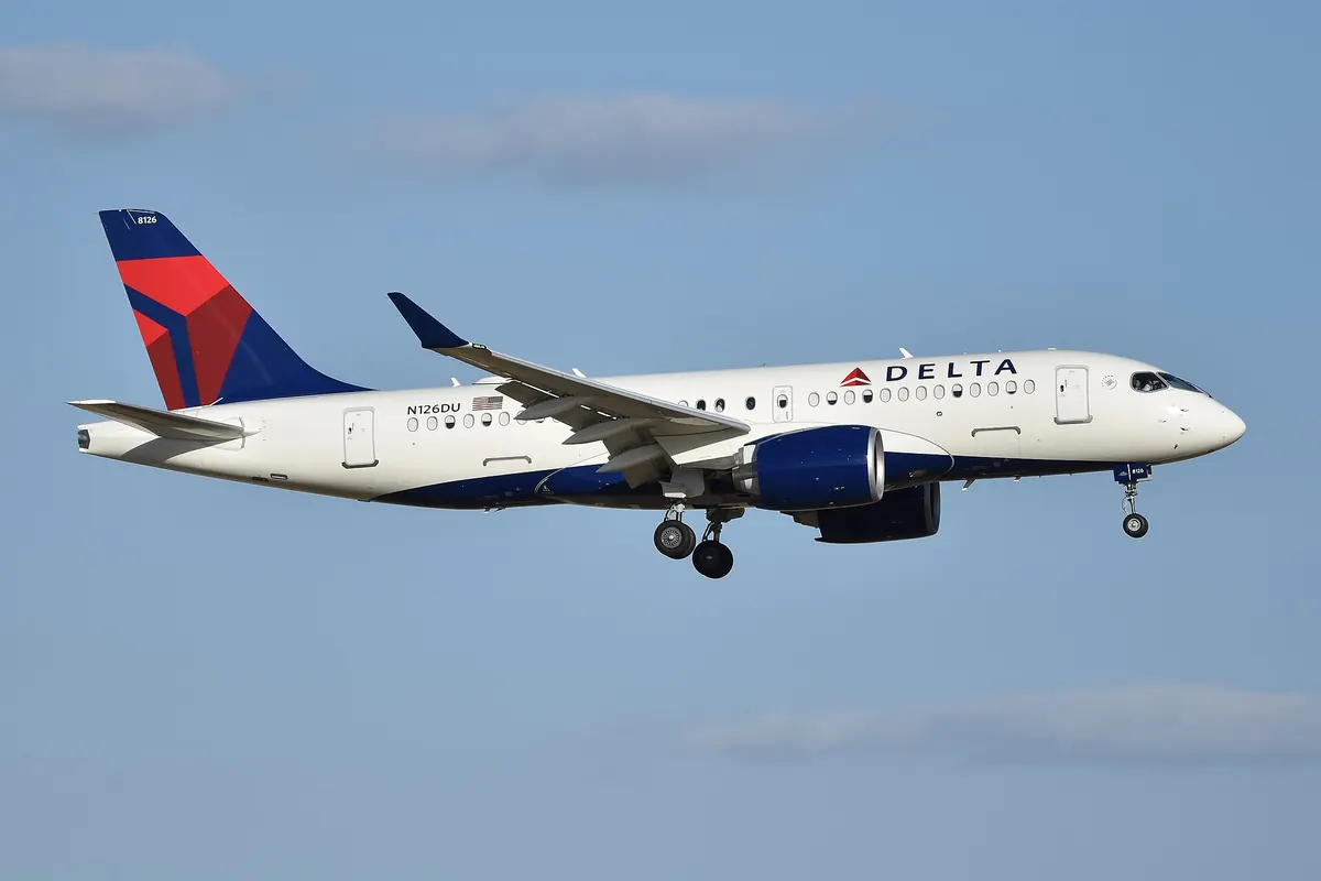 A Delta Air Lines Airbus A220 with a red and blue tail logo approaching to land