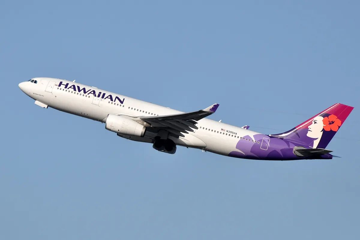 A Hawaiian Airlines Airbus A330 aircraft climbing after takeoff, with a purple tail featuring a woman's face design