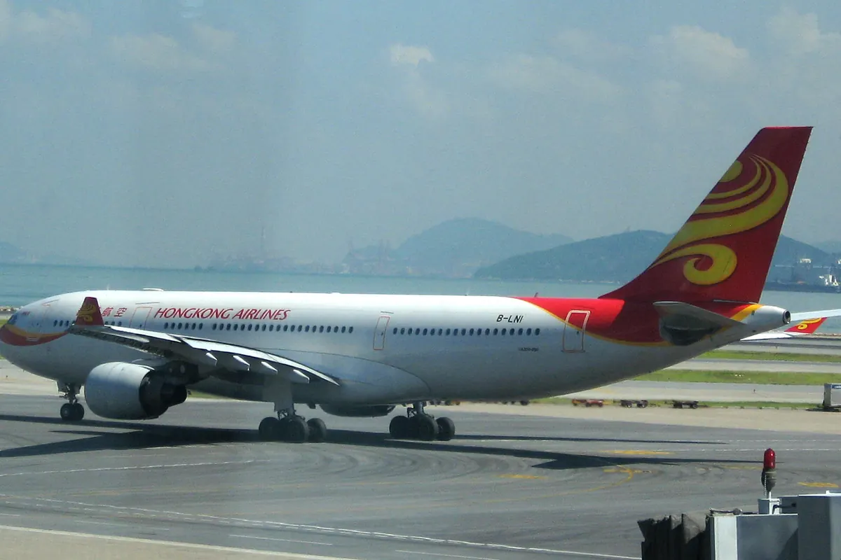 금색 소용돌이 로고의 빨간 꼬리를 가진 Hong Kong Airlines 항공기, 활주로를 주행
