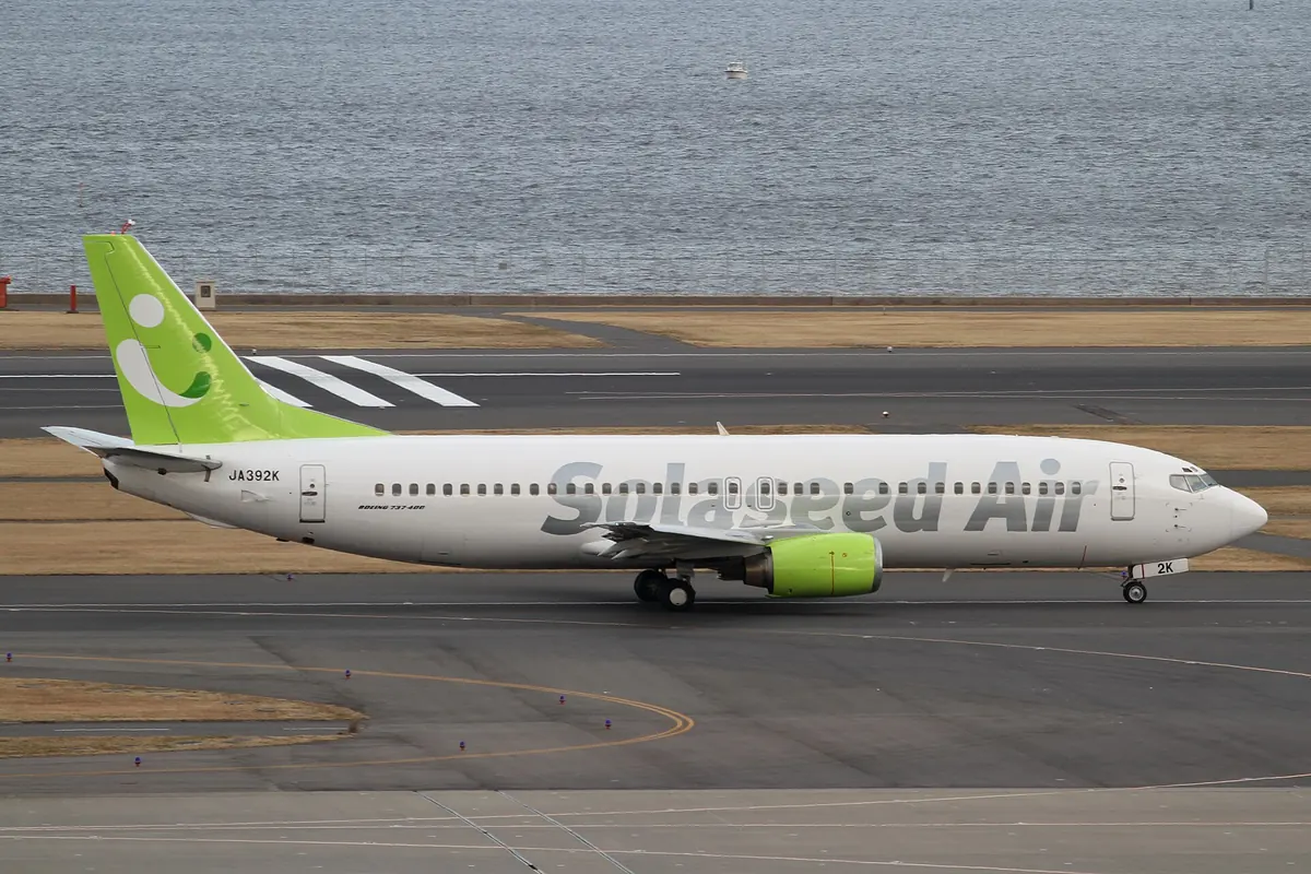 羽田空港で水辺を走行するソラシドエアのボーイング737型機、尾翼は緑色