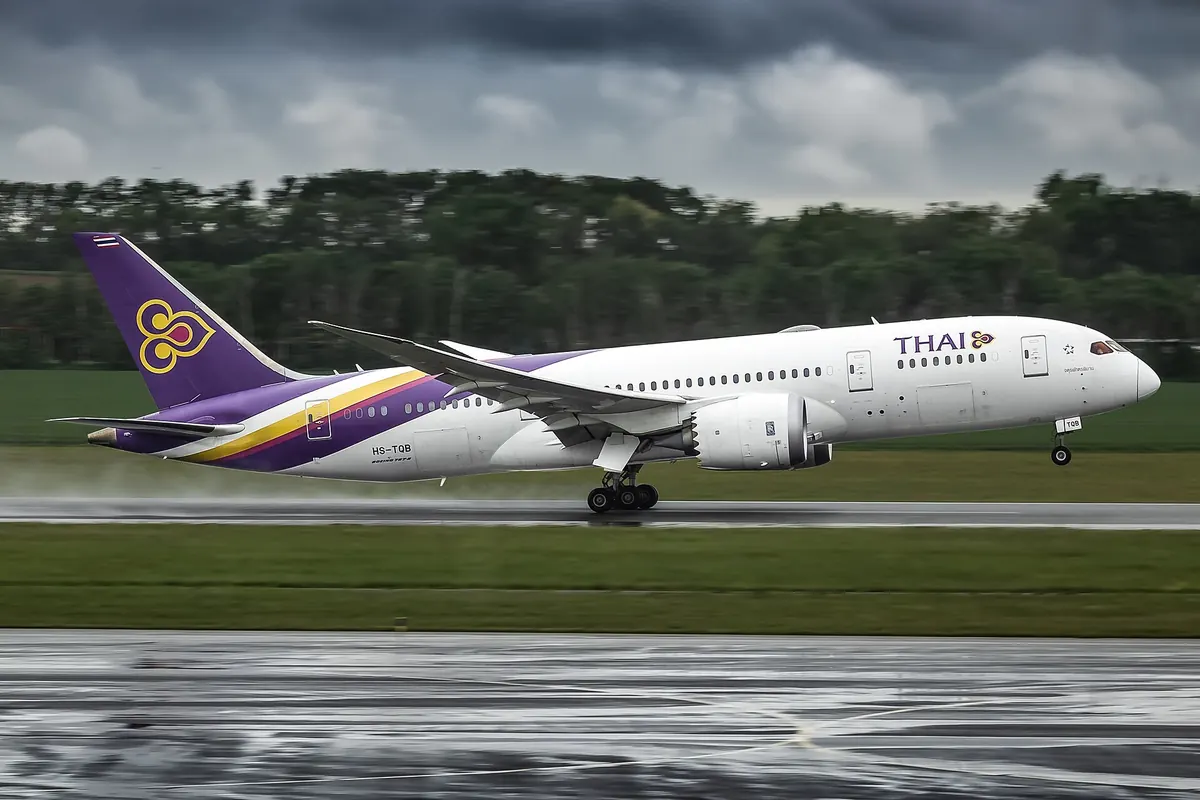 潮濕的跑道上，紫色尾翼與金色標誌的 Thai Airways 波音787-8