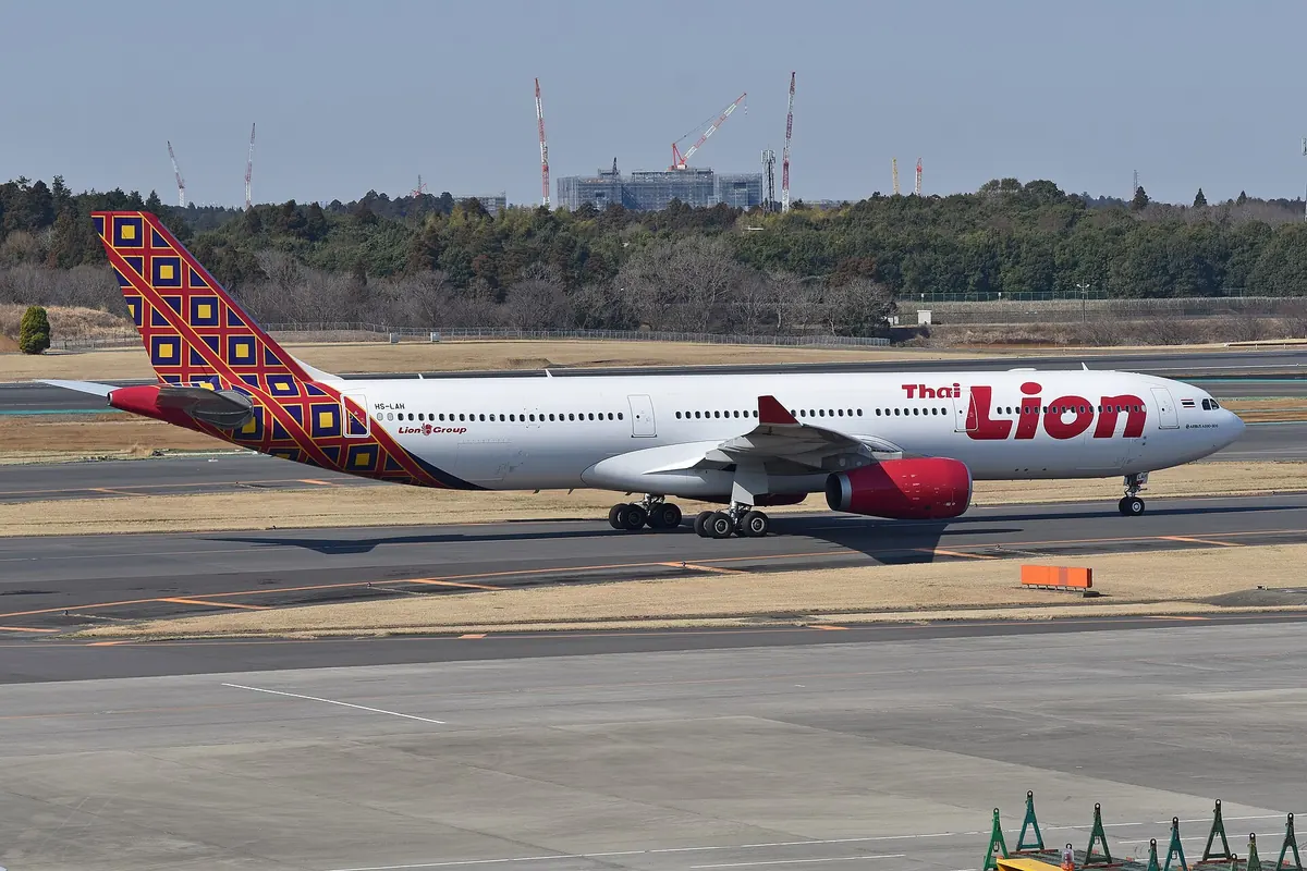 Thai Lion Air Airbus A330 aircraft on the tarmac with its patterned tail fin and trees in the background