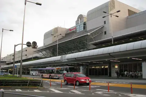 Exterior of Haneda Airport Terminal 1 building with buses and a car on the road in front of the entrance