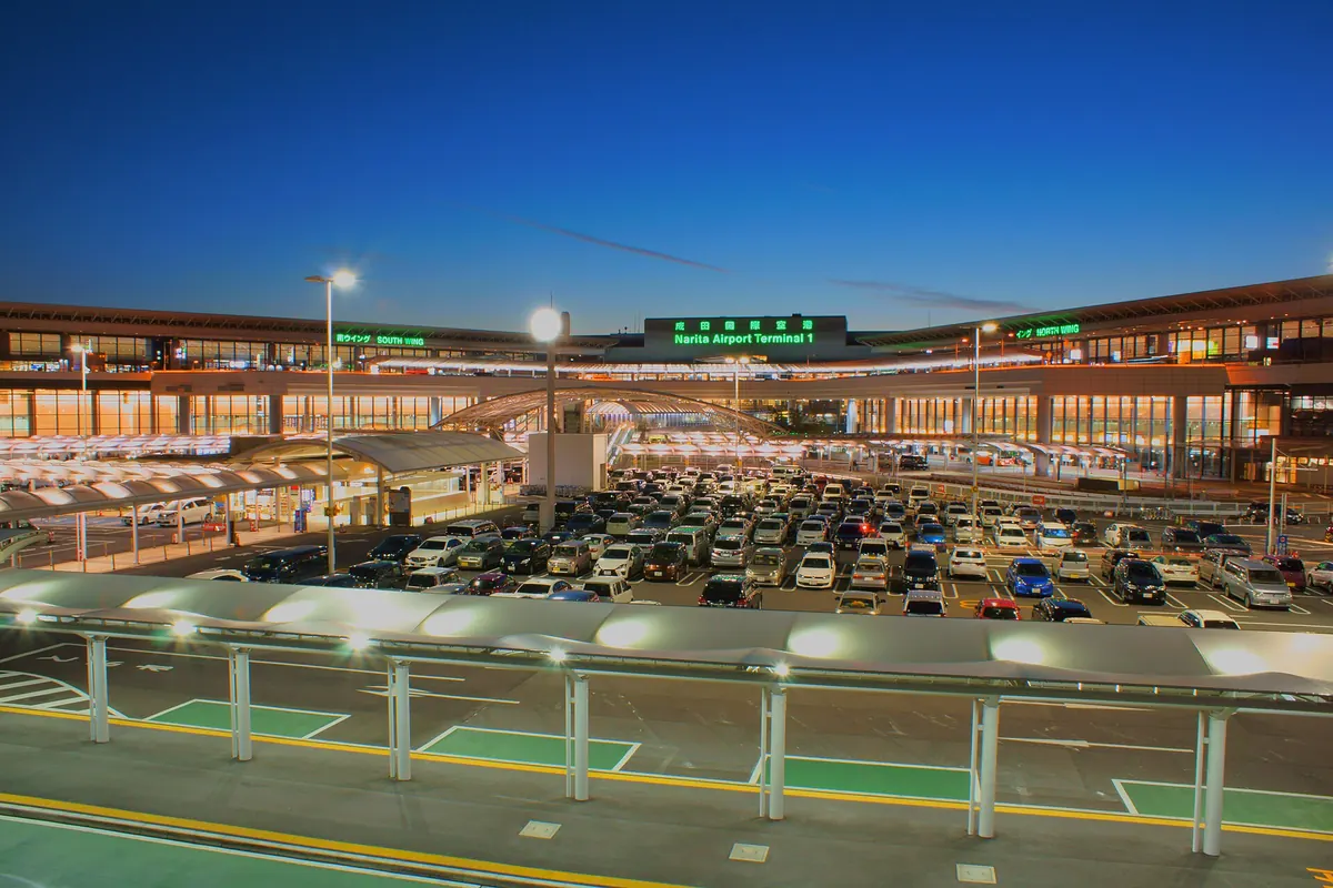 Exterior of Narita Airport Terminal 1 building illuminated at night with the parking lot in front
