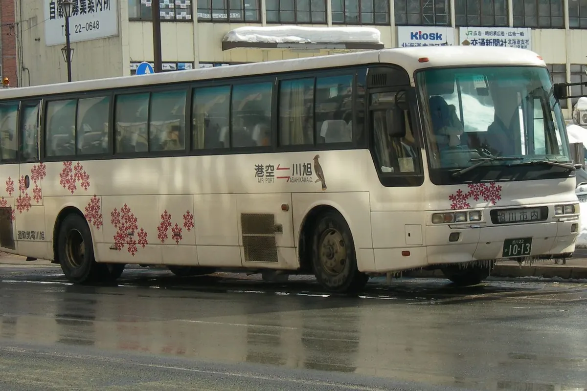 停在积雪街道上，印有红色雪花图案的白色旭川电气轨道机场巴士