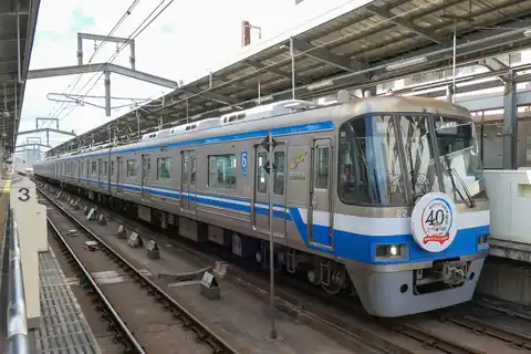 A silver Fukuoka City Subway train with a blue stripe at a station platform