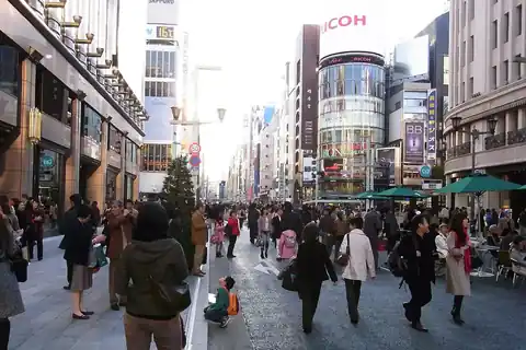 Pedestrians walking along Chuo-dori street in Ginza, Tokyo, lined with shops and buildings