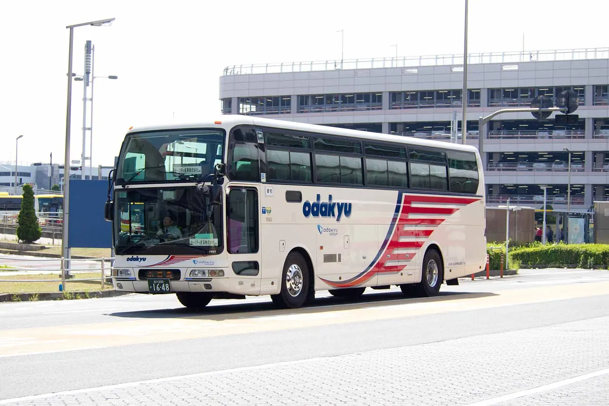 羽田空港の道路にいる、赤と青の帯が入った白い小田急箱根高速バス