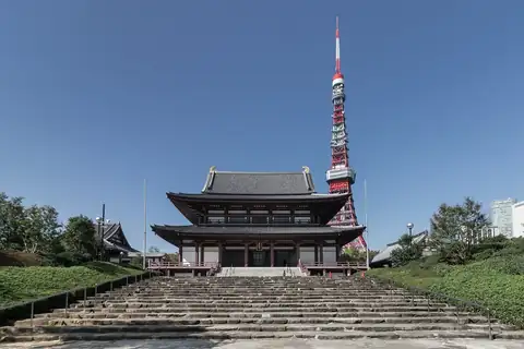 The main hall of Zojo-ji Temple at the top of a long stone staircase, with Tokyo Tower rising behind it