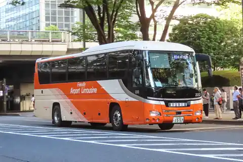 An orange and white Airport Limousine bus with a destination sign on a street in Shinjuku, Tokyo