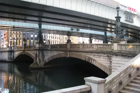 Stone-arched Nihonbashi bridge in Tokyo spanning a river, with an elevated expressway passing overhead