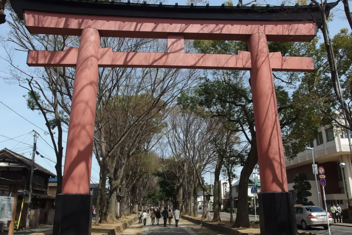 大宮の氷川神社にある大きな赤い鳥居と、並木道を歩く人々