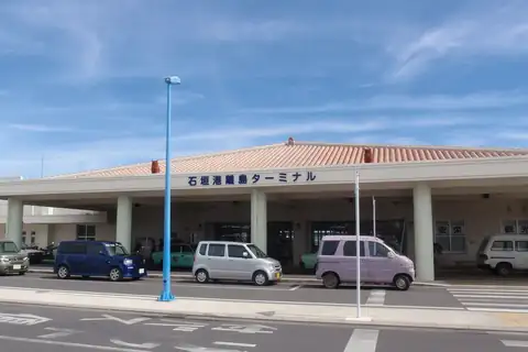Ishigaki Port ferry terminal building with a Japanese sign and cars parked in front