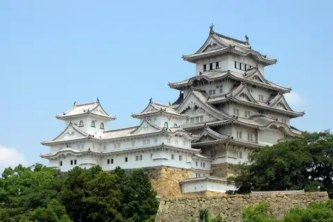 Himeji Castle's white tiered keep rising above stone walls and trees