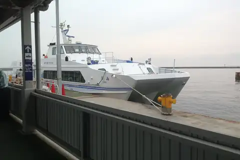 The Kobe-Kansai Airport Bay Shuttle catamaran docked at a covered pier with a Gate 2 sign for Kobe