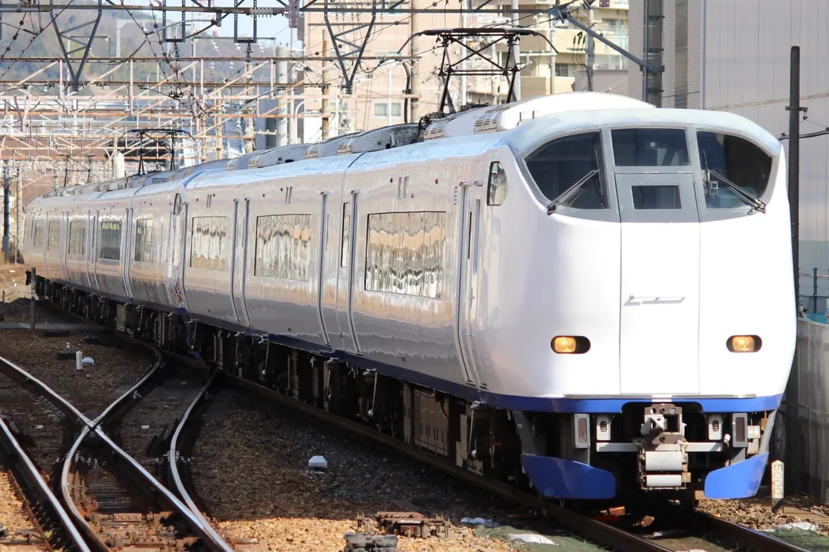 行驶于京都线、后方可见架空电线与建筑的JR西日本 HARUKA 特急列车
