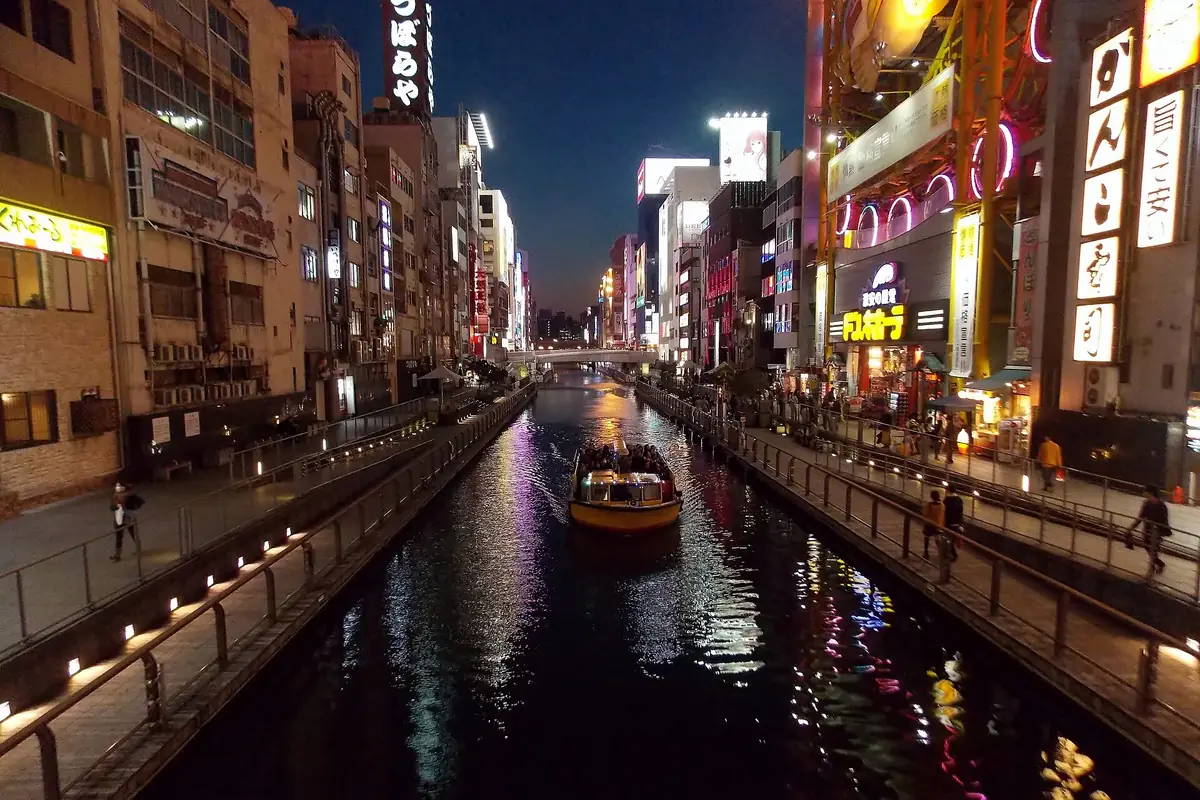 夜晚的大阪道顿堀川，沿岸亮灯的招牌与游船