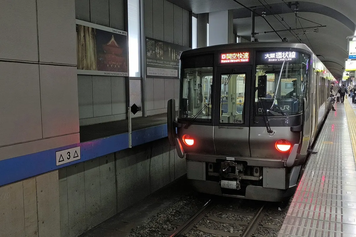 停靠在車站月台、車頭顯示「關西機場快速」的JR西日本223系列車