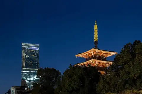 Abeno Harukas skyscraper beside the illuminated five-story pagoda of Shitennoji temple in Osaka at dusk