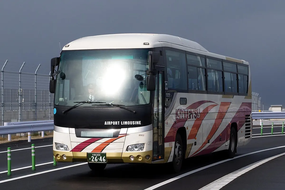 フロントガラス下にAIRPORT LIMOUSINEの文字がある、赤とオレンジの帯が入った白い近鉄の空港リムジンバス