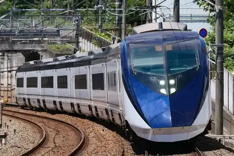 A Keisei Skyliner AE series train with a blue front on a curved track under overhead wires