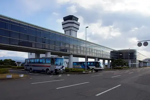 Nagasaki Airport terminal with a glass walkway, control tower and two white coach buses parked outside