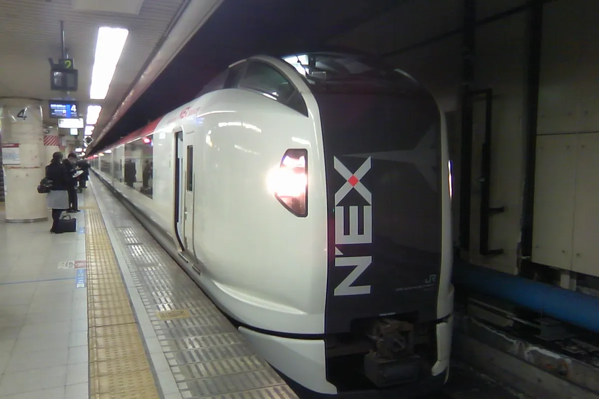 駅のホームに停まる、白い車体で先頭部分が濃い色のJR成田エクスプレス(N'EX)