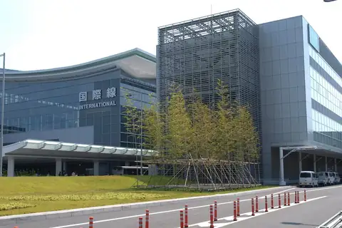 Haneda Airport terminal with an International sign, glass facade and trees