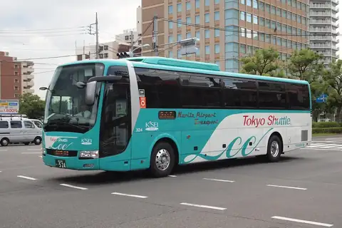 Turquoise and white Tokyo Shuttle airport bus with Narita Airport Transport lettering on a city street