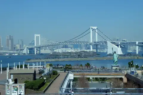 Rainbow Bridge and a Statue of Liberty replica by the water in Odaiba, Tokyo