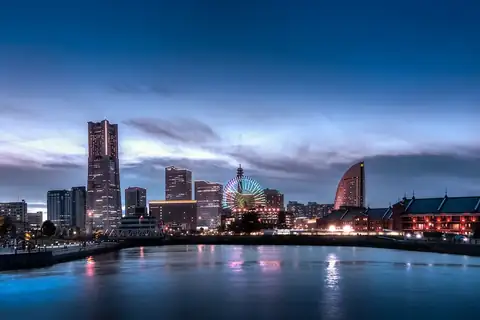 Minato Mirai skyline in Yokohama at night, with lit-up towers, a Ferris wheel and red-brick buildings across the water