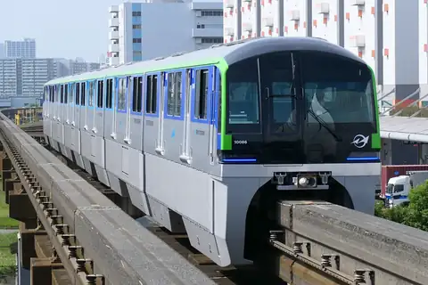 A Tokyo Monorail 10000 series train with green and blue stripes, seen head-on on its elevated track