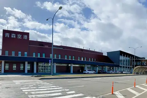 Exterior of the Aomori Airport terminal building with its name sign and a parking area in front