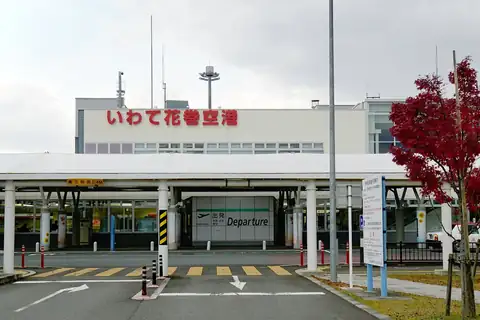 Entrance of Iwate Hanamaki Airport terminal building with a departure sign and a red maple tree beside it