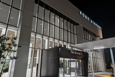 Exterior entrance of Kobe Airport Terminal 2 at night with illuminated KOBE AIRPORT signage on the building