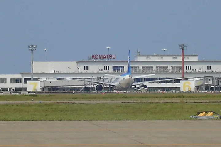 Komatsu Airport terminal building viewed across the runway with an airplane in front and KOMATSU lettering on the facade