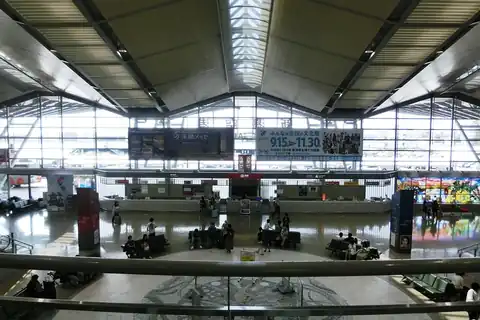 Departure lobby inside Niigata Airport terminal with a high truss ceiling, seating area and travelers walking through
