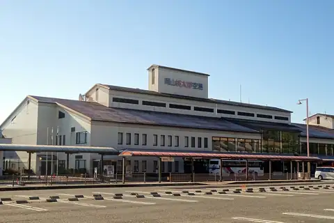 Exterior of Okayama Airport terminal building with buses parked under the entrance canopy