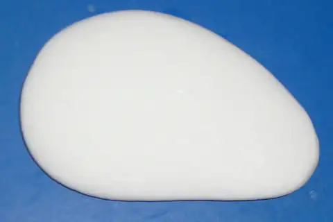 A single oval-shaped white bar of soap on a blue background