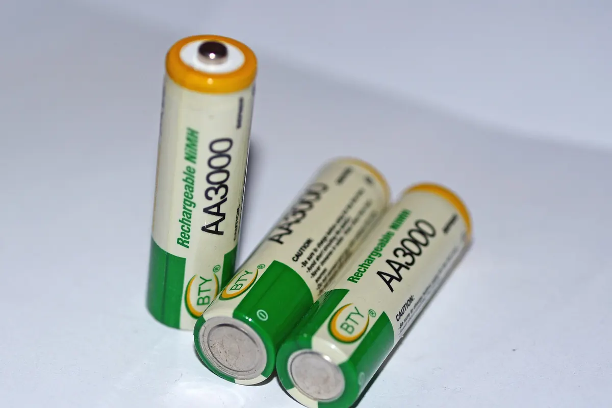 Three rechargeable AA batteries, one upright and two lying down, with green and white labels on a white background