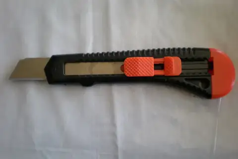 A utility knife with the blade extended, resting on a white cloth