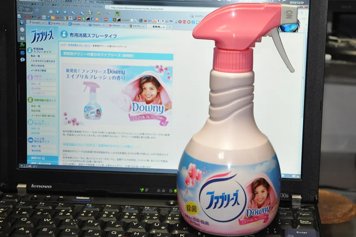 ノートパソコンの画面の前にある、ピンクのトリガースプレー式ファブリーズ布用消臭剤