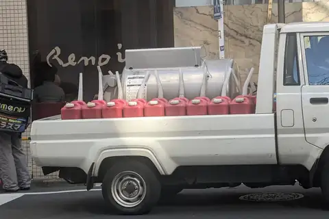 Red fuel cans lined up on the back of a white light truck in Ebisu