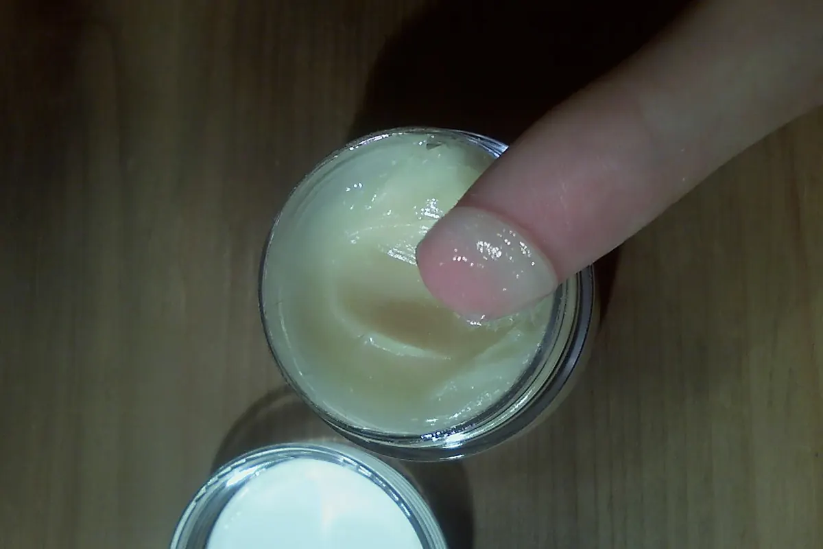 手指伸入木桌上一罐已打开的淡色乳霜状发蜡中